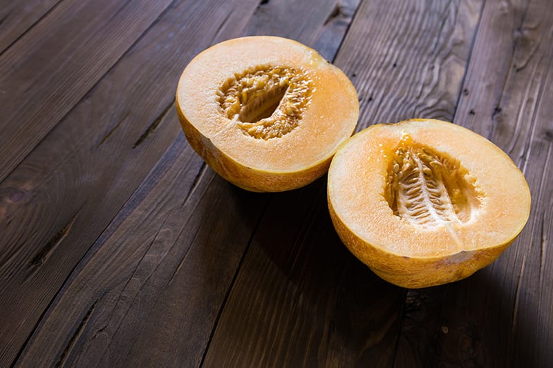 Melon cut in half on a wooden surface